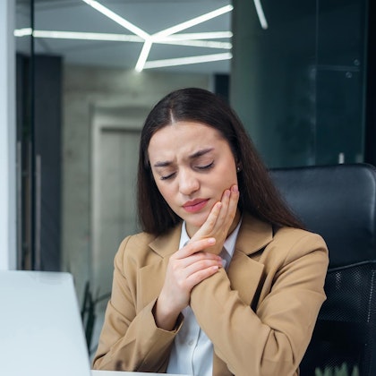 Working woman holding jaw in pain
