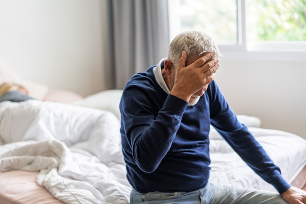 Nursing home resident with his head in his hands