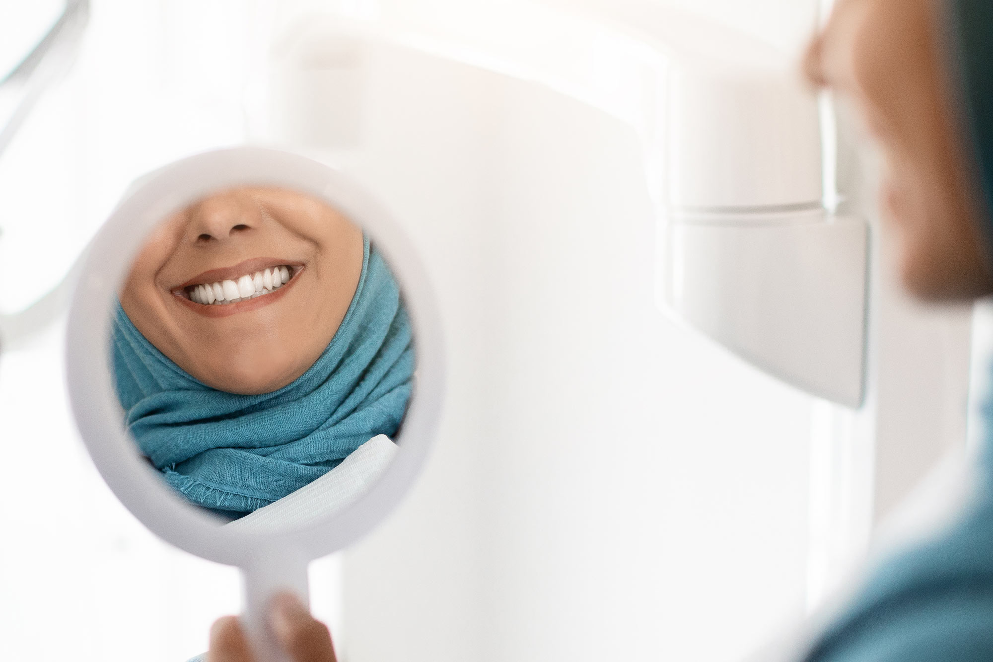 woman smiling in handheld mirror