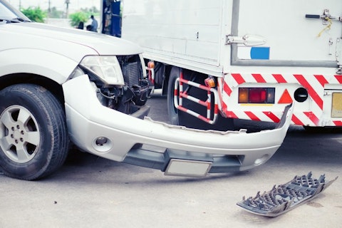 Car with broken bumper and a truck in the background