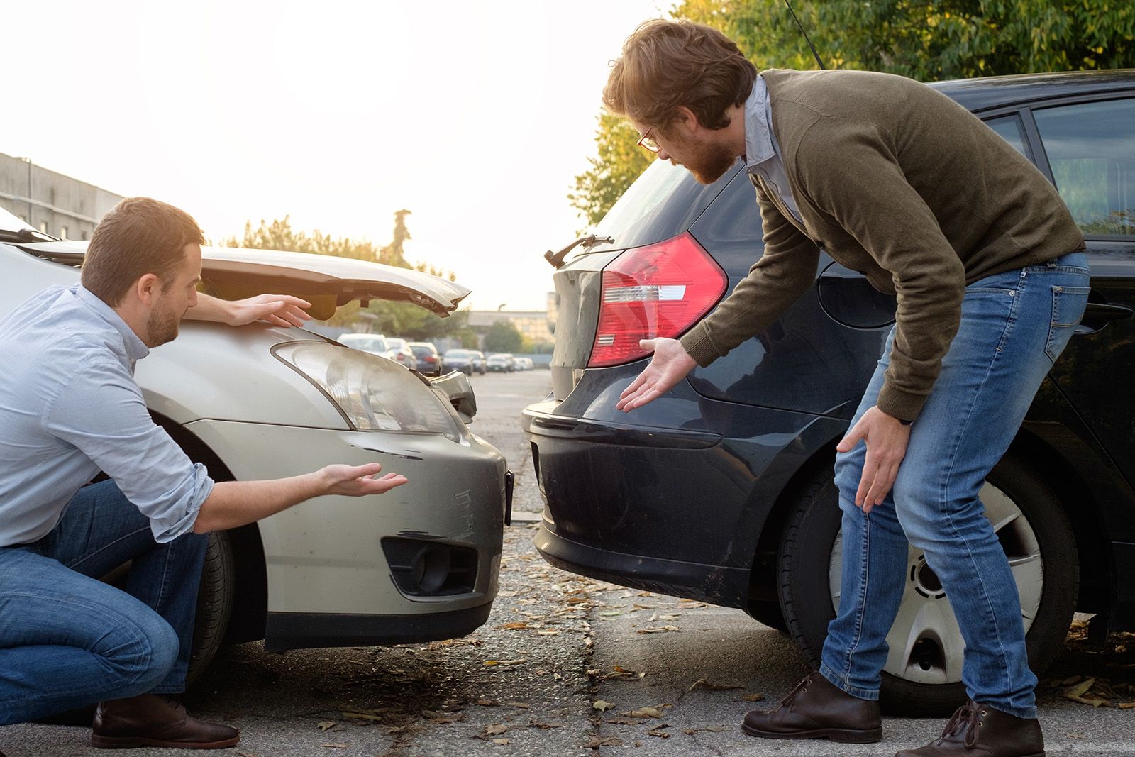 two men looking at their cars after an accident