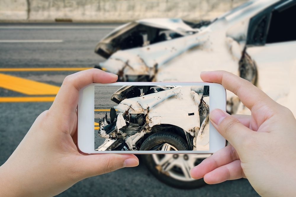 Close up of person taking a picture of car accident on road