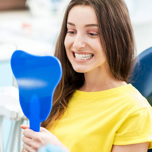 Woman looks at teeth in mirror