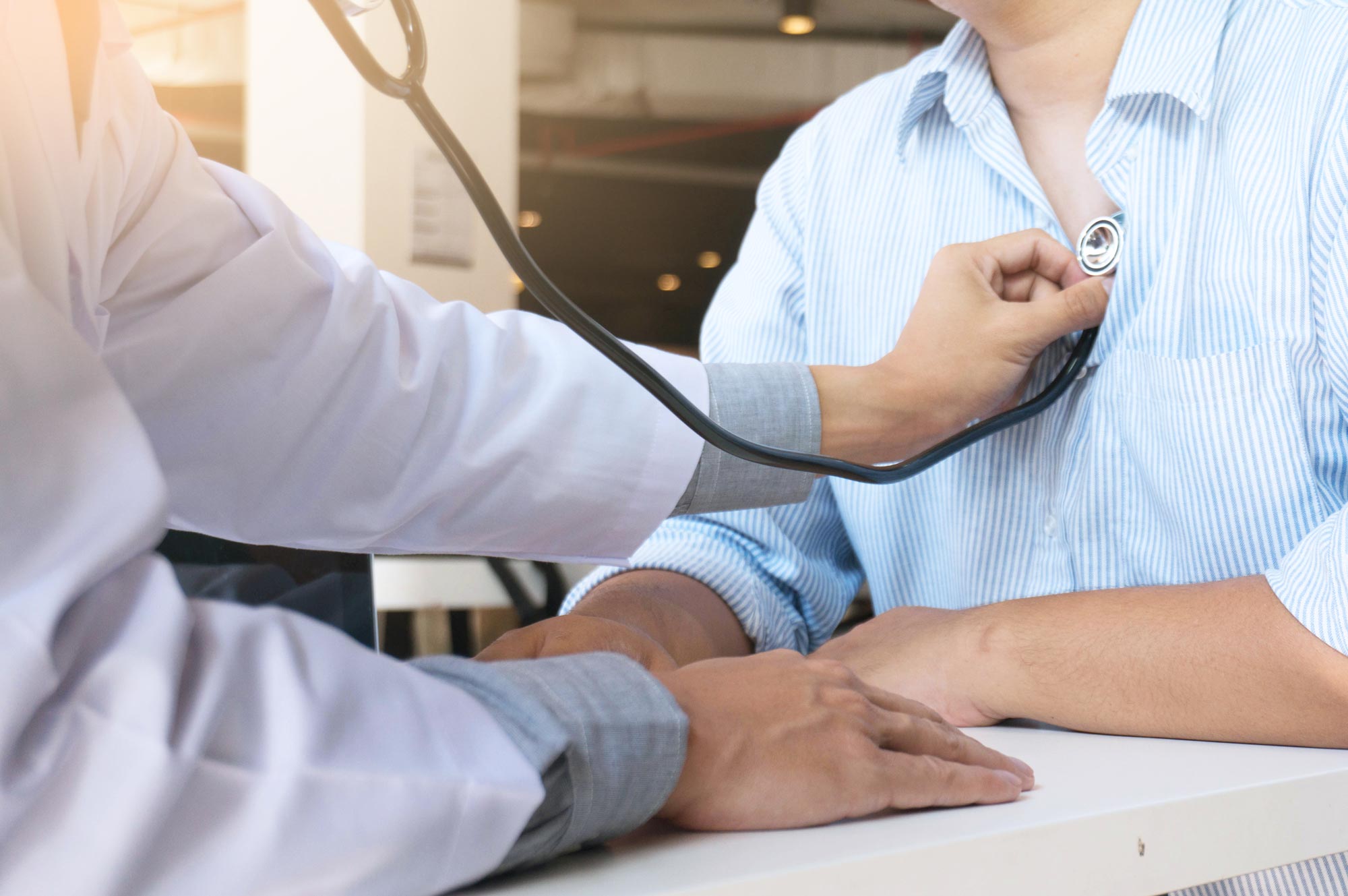 Doctor listening to patient's heart through stethoscope