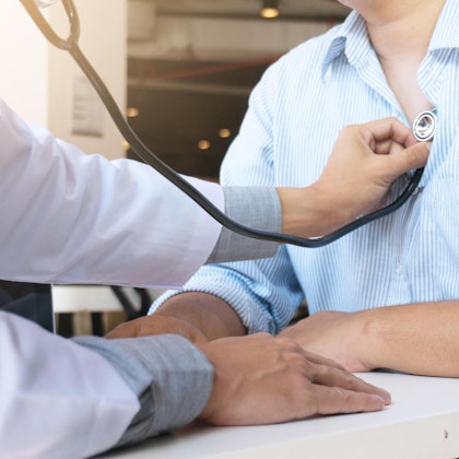 Doctor listening to patient's heart through stethoscope