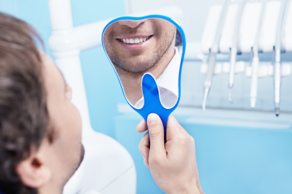 A patient looking in the mirror at his dental implants.