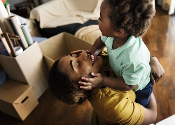 Mother lifting up a child surrounded by moving boxes