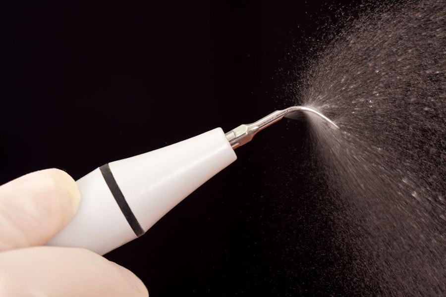 Close-up of a rotary tool used in scaling and root planing as it sprays water.