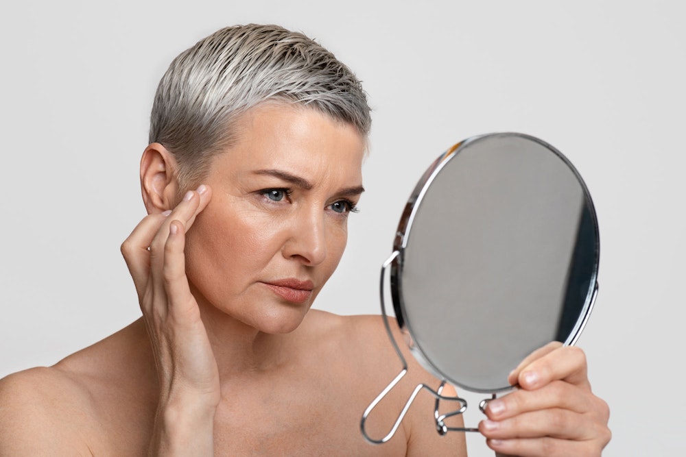 Mature woman looking in the mirror at wrinkles