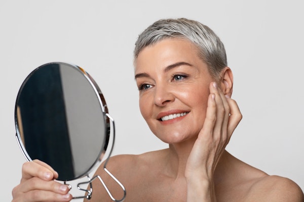 Mature woman admiring facial cosmetic surgery in mirror