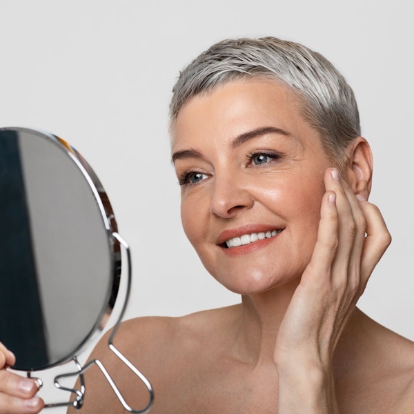 Mature woman admiring facial cosmetic surgery in mirror