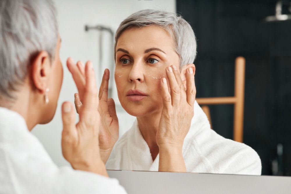 Woman applying cream to face after facelift