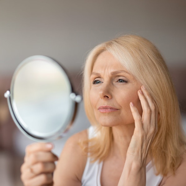 Woman looking thoughtfully in mirror