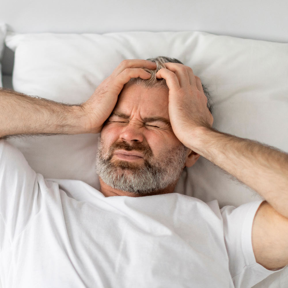 Man with sleep apnea holding head because of headache