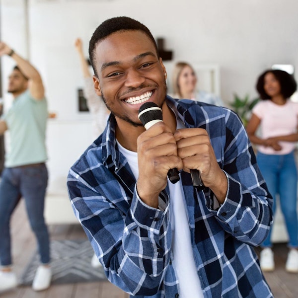 Smiling man singing karaoke with friends
