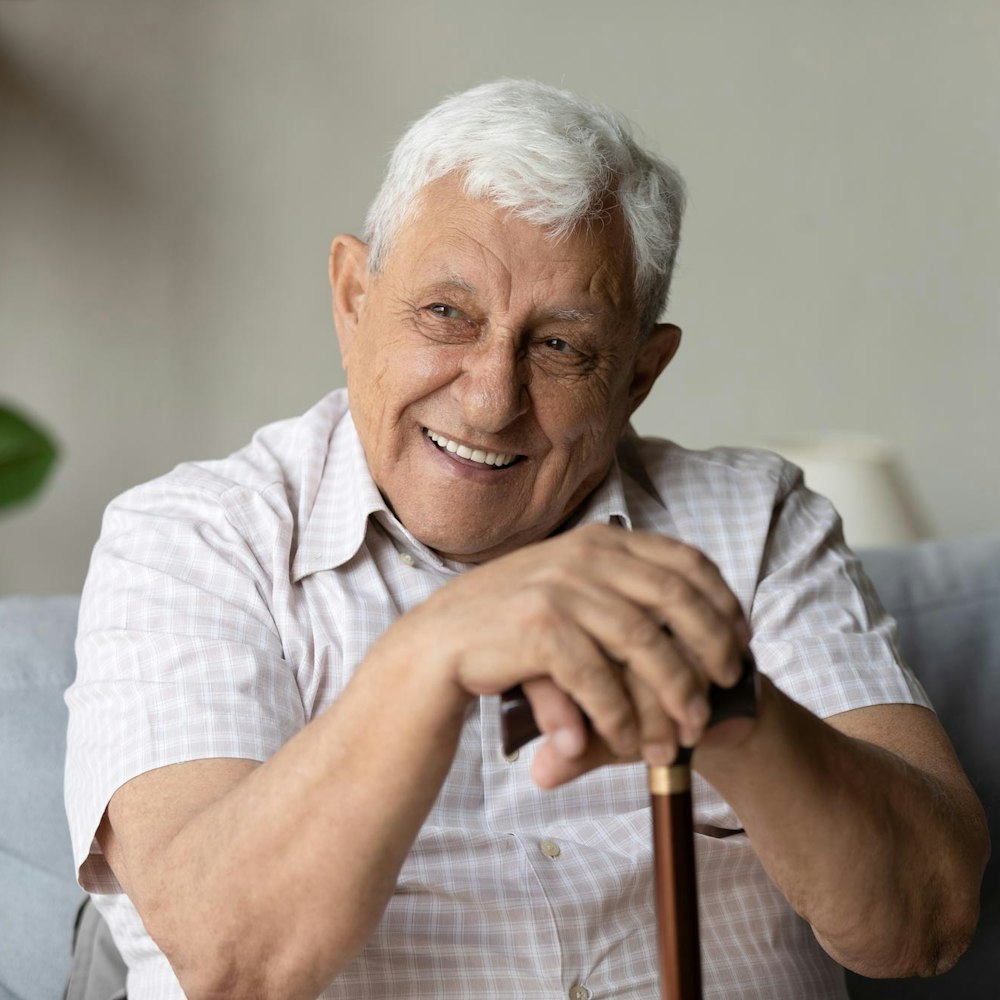 Smiling elderly man after full mouth reconstruction holding onto cane