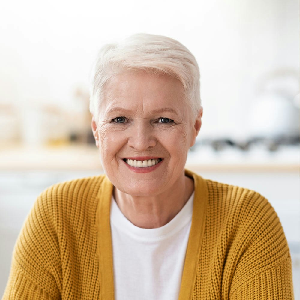 older woman in orange sweater smiling