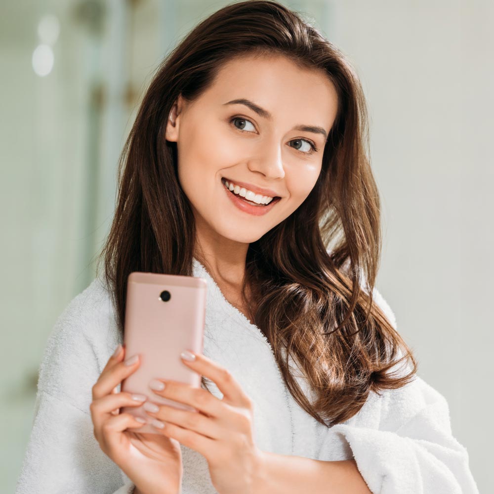 Smiling woman taking a selfie in bathroom mirror