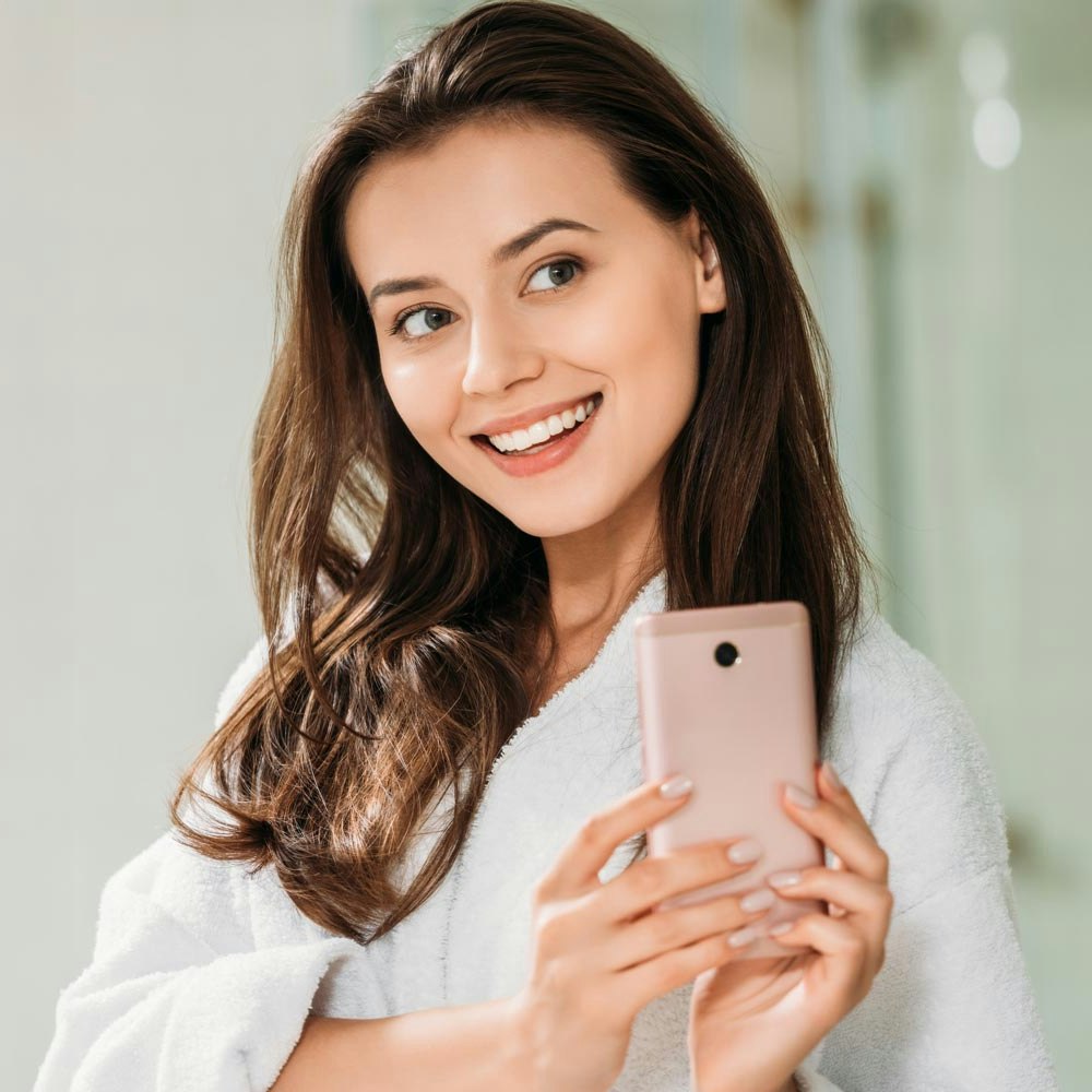 Smiling woman taking a selfie in bathroom mirror