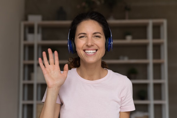 Woman wearing headphones smiling and waving