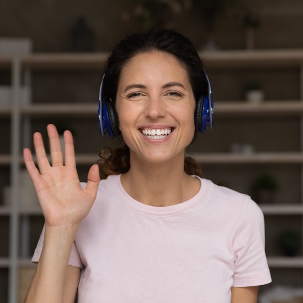 Woman wearing headphones smiling and waving