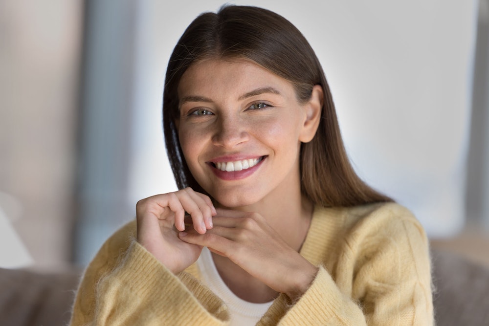 Smiling woman with teeth whitening wearing a yellow sweater