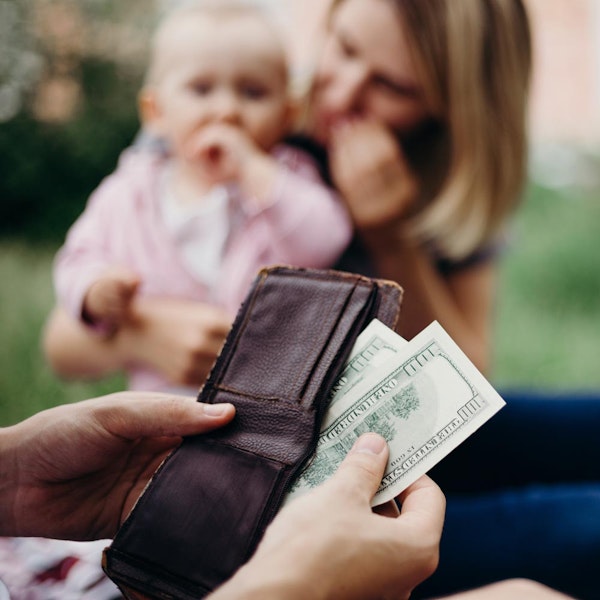 Alimony money coming out of wallet with mother and child in the background