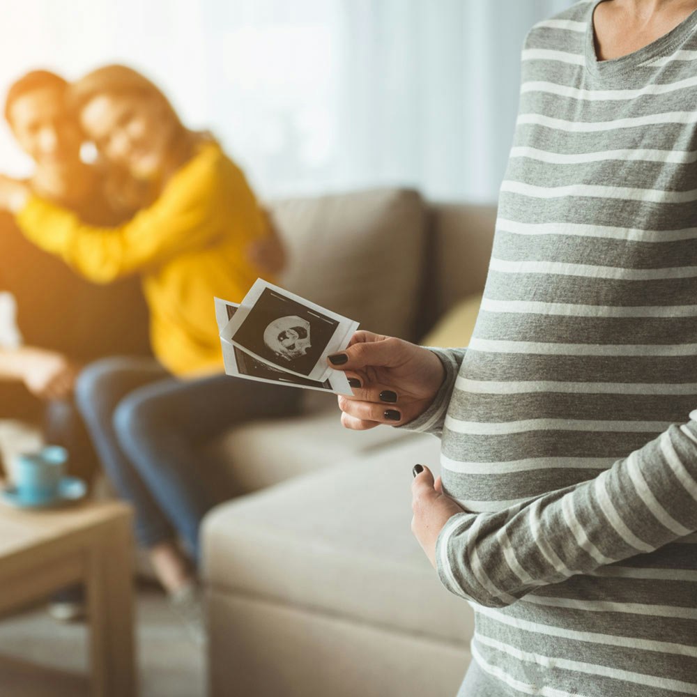 Close up of surrogate mother and couple in the background