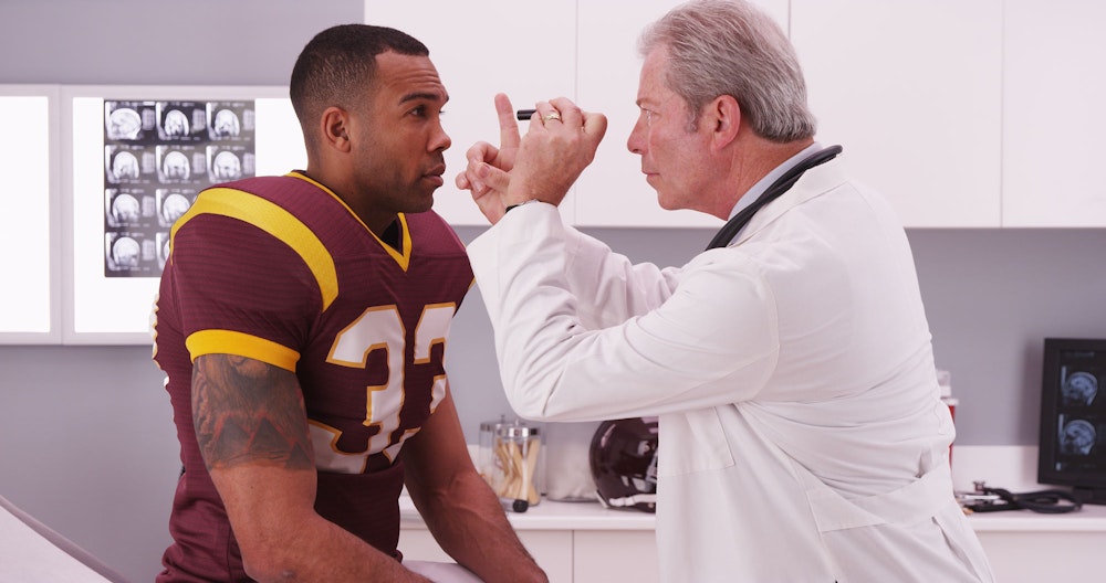 American Football player's eyes being checked after an accident