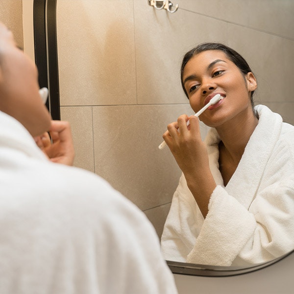 Woman looking in the mirror as she brushes her teeth