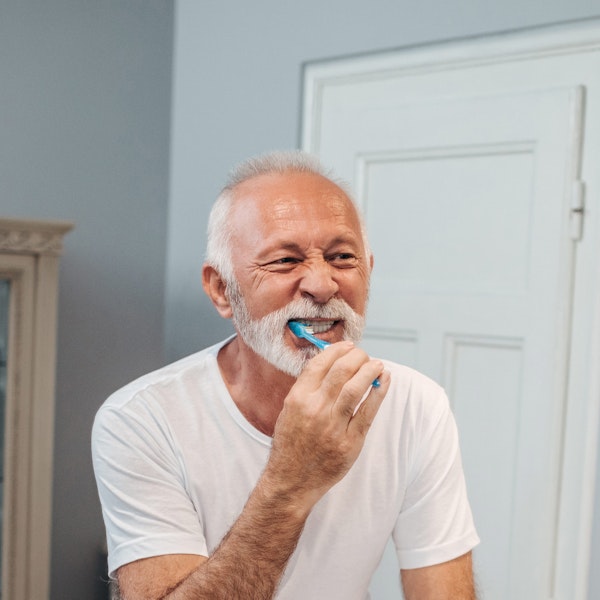 Mature man brushing teeth in bathroom