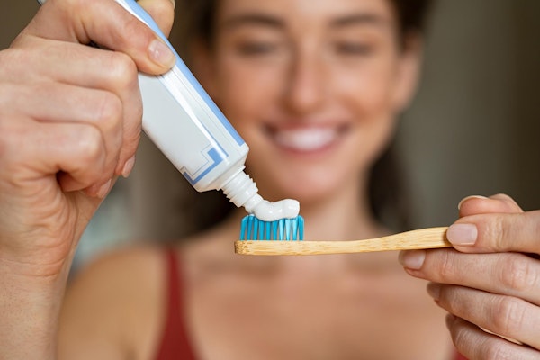 Woman putting toothpaste onto toothbrush