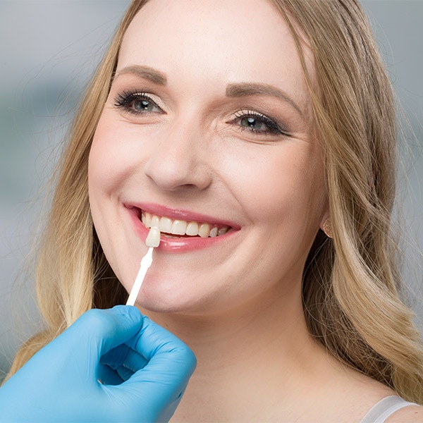 Doctor comparing color of porcelain veneer to patient's teeth