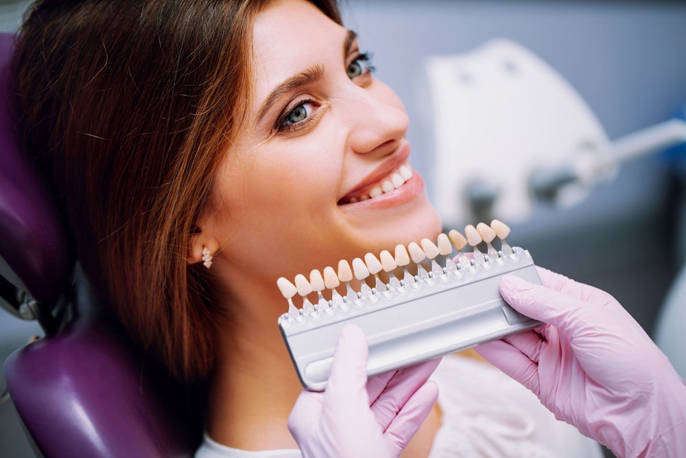 Smiling young woman comparing different veneers