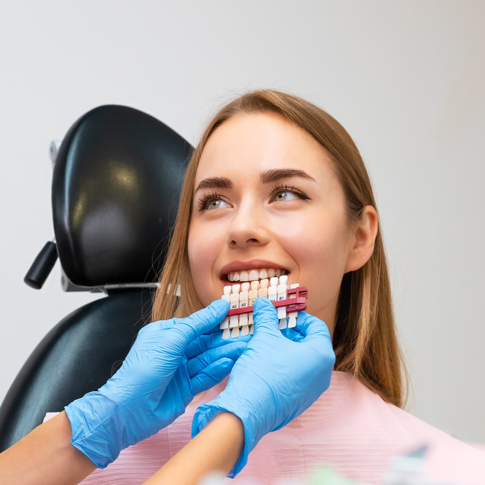 Smiling patient comparing veneer shades