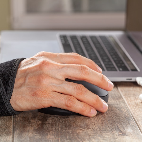 Person wearing a wrist brace while using a computer mouse