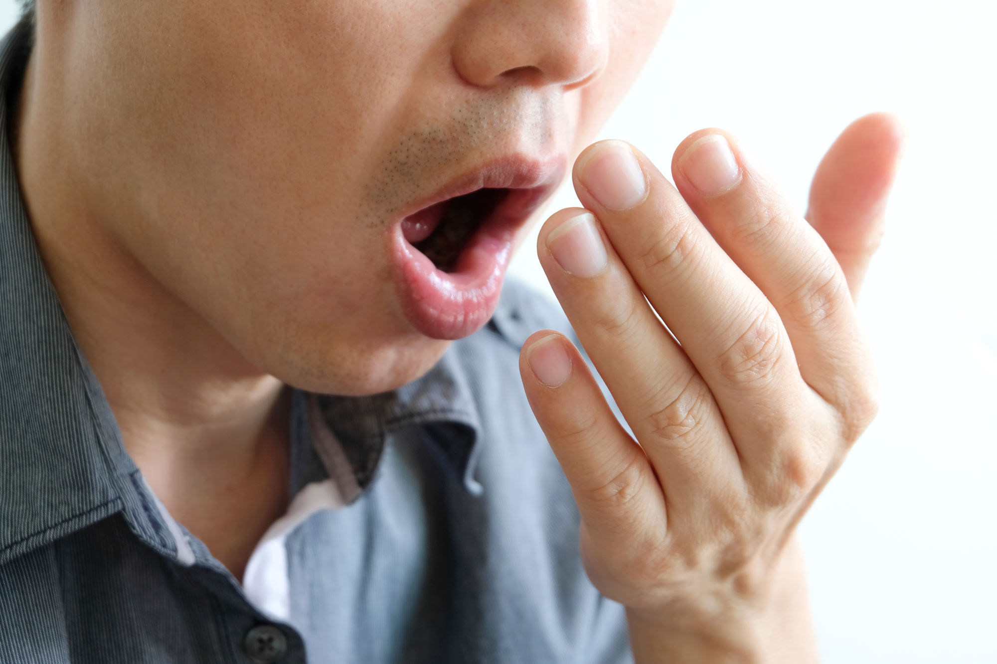 a person breathing into their hand trying to smell their breath